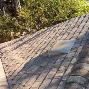 A roof with a brick pattern and a metal vent.